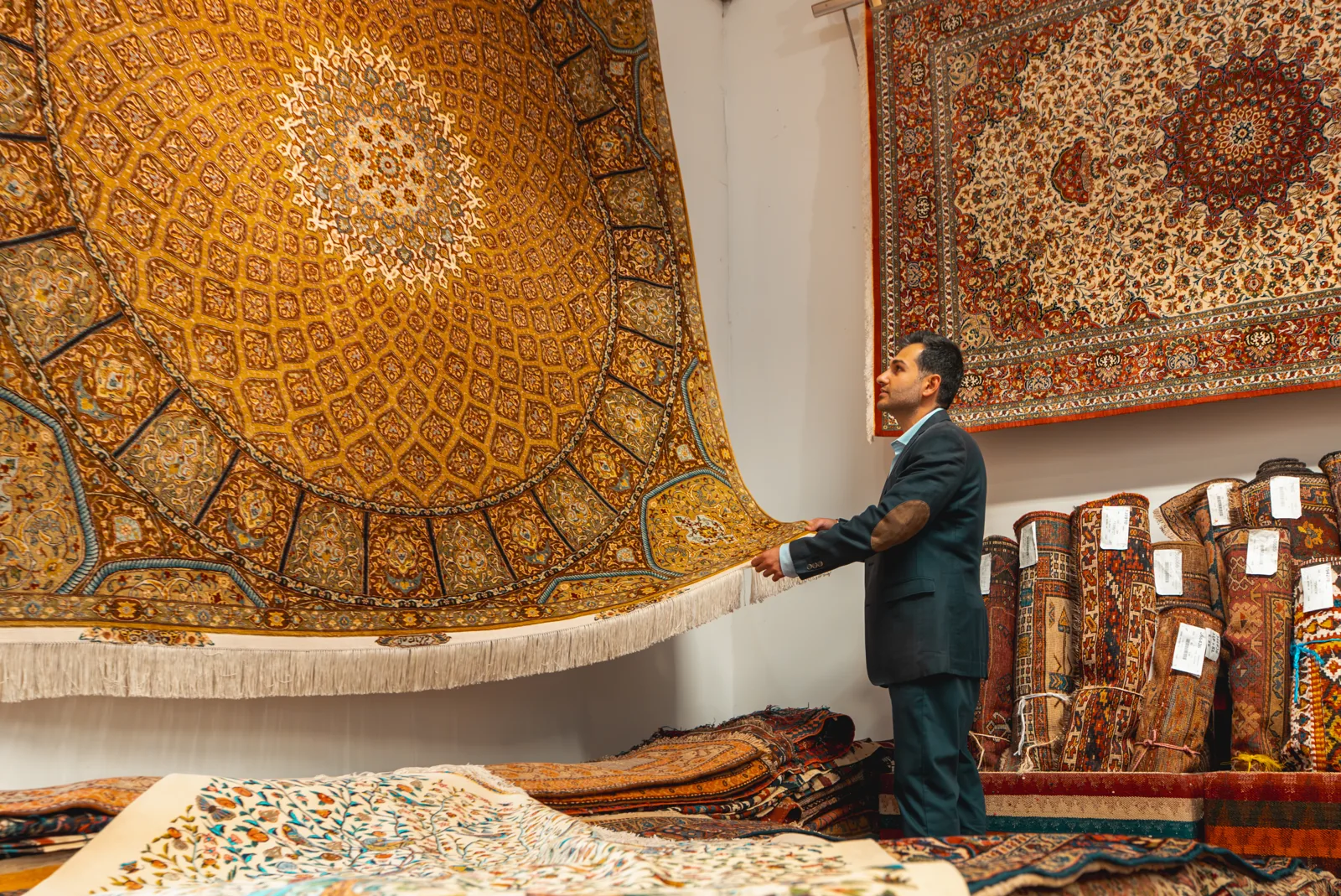 A large patterned rug being held for viewing in the showroom