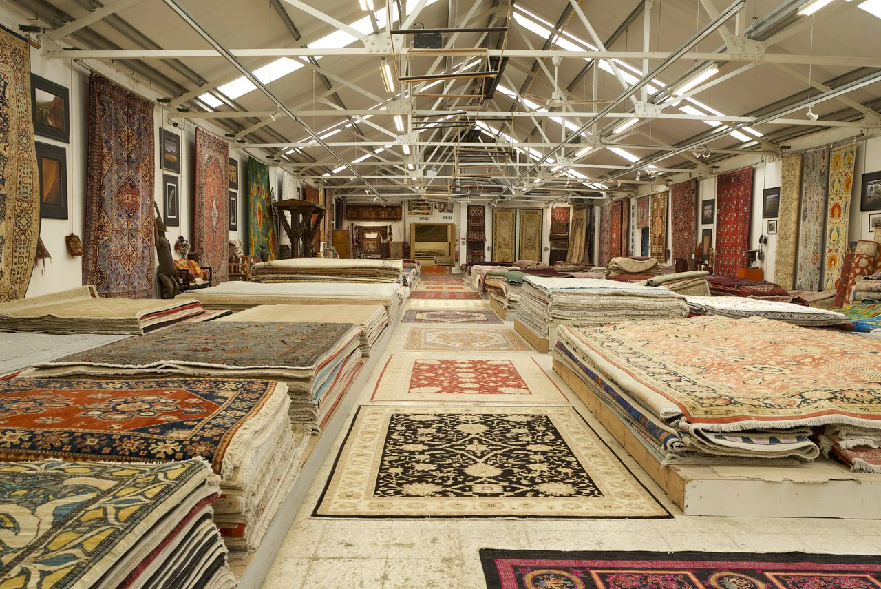 The main showroom hall with carpets stacked either side of the central aisle